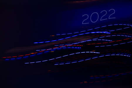 Abstract background of Christmas lights with long exposure. Colorful 2022 number on black background