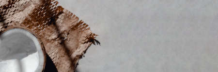 Half coconut on craft paper under sunlight. Top view. Banner