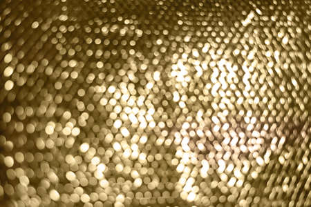 Holiday gold glowing glittering backdrop. Defocused background with glitter. Blurred bokeh.の写真素材