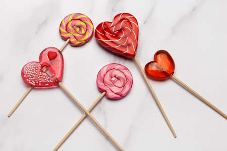 Many hearts shaped lollipops on white marble background. Candy Love concept. Valentine's Day.の写真素材