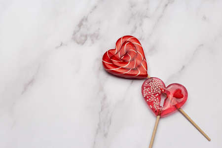 Two heart shaped lollipops on white marble background. Candy Love concept. Valentine's Day.の写真素材