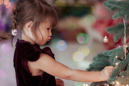 Happy little girl with christmas toy near a xmas tree.の写真素材