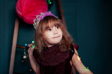 little girl with garlands on christmas background.の写真素材