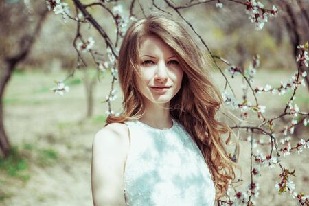 Beautiful spring blond girl in blooming tree.の写真素材