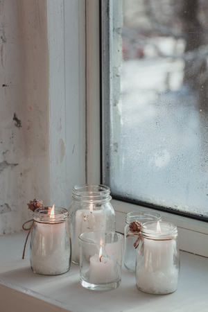 Advent candles burning on the white windowsill. Christmas still life.の写真素材