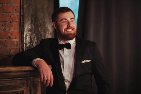 portrait of young handsome smiling ginger man with beard in the dark room.の写真素材