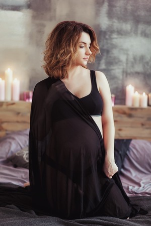 Pregnant women on the bed in a room with candlesの写真素材