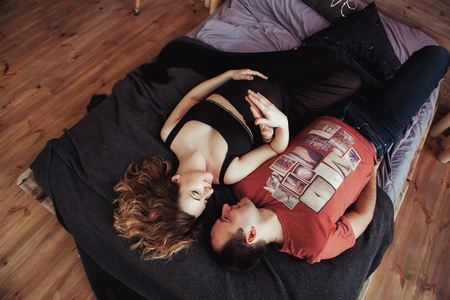 view from the top, young couple embracing in bed, tender. The woman is pregnantの写真素材