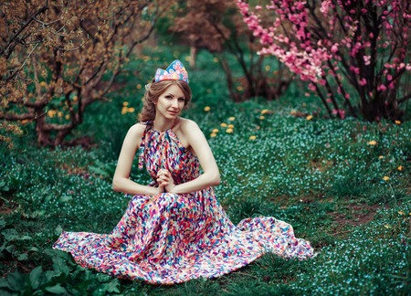 beautiful woman with decoration in her hair in the spring park with blossoming cherry treesの写真素材