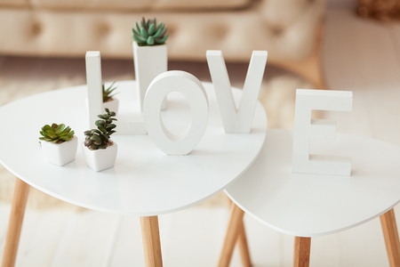 The word Love in white letters on the interior volume background. Beige white sofa and coffee table in the roomの写真素材