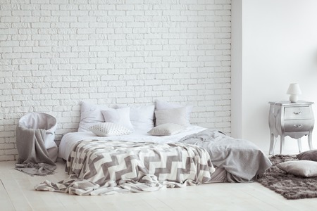 Bedroom interior with a brick wall with a bed and bedside tablesの写真素材