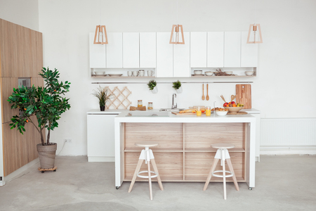 interior of small white kitchen with fresh fruit, two glasses of orange juice, baguette, red caviar, croissant and cookies with chocolate chips on the tableの写真素材