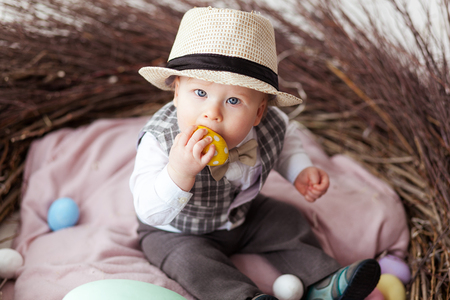 Baby in Easter nest with eggs in in a suit and hat. Easter holiday concept: nest with baby