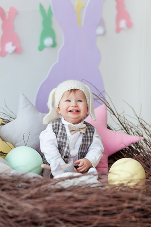 funny baby boy dressed in Easter bunny suit lying in a nest