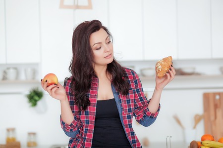 Diet. Dieting concept. Healthy Food. Beautiful Young Woman choosing between Fruits and Sweets. Weight Lossの写真素材