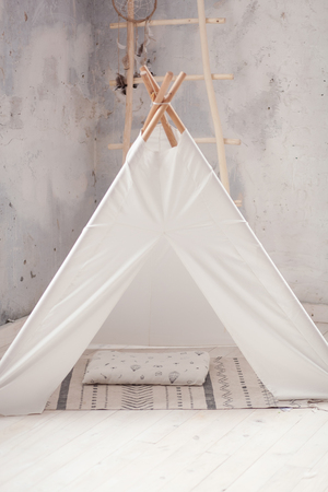 Childen's room corner with a beautifully decorated play tipi tent and a round grey carpet.の写真素材