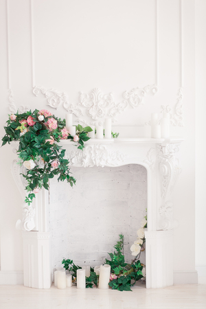 Classic white Interior of living room with fireplace and bouquet of spring flowers on itの写真素材