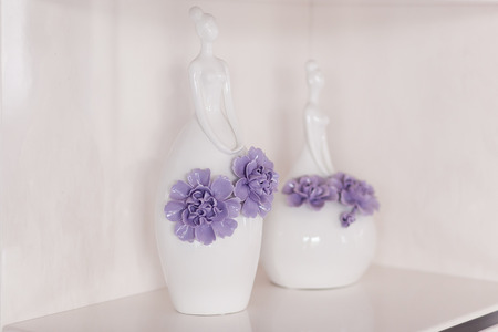 Two vases in the form of a woman with flowers stand on a shelfの写真素材