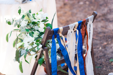 Decorative red, blue and white ribbons on chair. Decorated chairs with red bows in a row.の写真素材