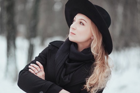 Woman winter snow nature portrait in black coat and hatの写真素材