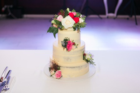 White wedding cake with flowers on table in restaurantの写真素材