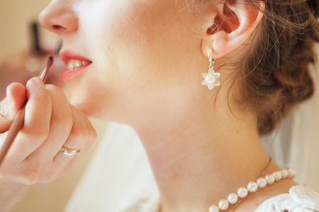 Wedding makeup artist making a make up for bride. Beautiful sexy model girl indoors. Beauty woman with curly hair. Female portrait. Bridal morning of a cute ladyの写真素材