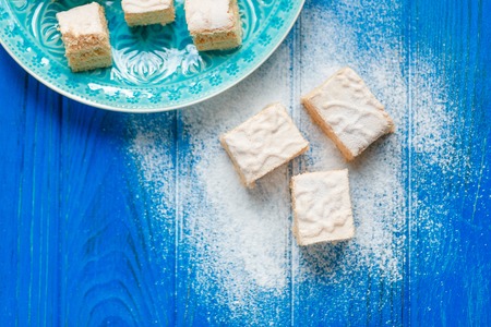 Biscuit cake pie apple candy pastila on blue wood cutting board background. Small square pieces paste. Top view photoの写真素材