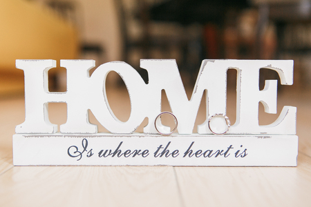 Two golden wedding rings on wooden letters HOME. Standing on floor indoorの写真素材