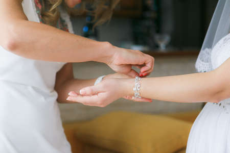 Girlfriend helps to dress the bride a bracelet on a hand befor wedding ceremonyの写真素材