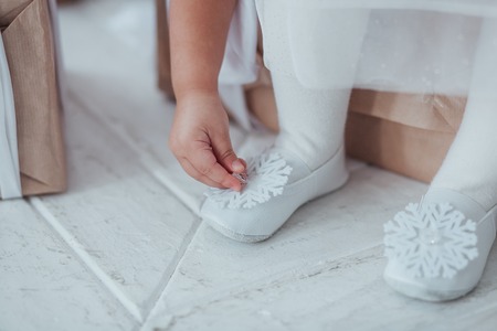 Closeup of young ballerina legs, sit in pointe shoes with snowflake decor at white wooden floor background. Ballet practice.の写真素材