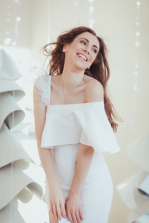Beautiful young model smiling and posing at the photo studio, fashion fabric christmas tree on background.の写真素材