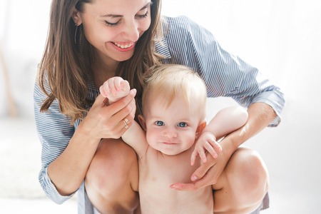 Mother with baby at home. Happy family with newborn playing indoorsの写真素材