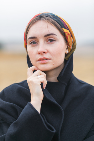 Portrait of a beautiful young woman in black coat in a field. Autumn fall seasonの写真素材