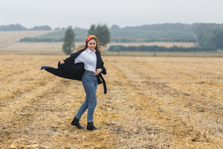 Beautiful smiling woman in a field at sunset. Autumn fall seasonの写真素材