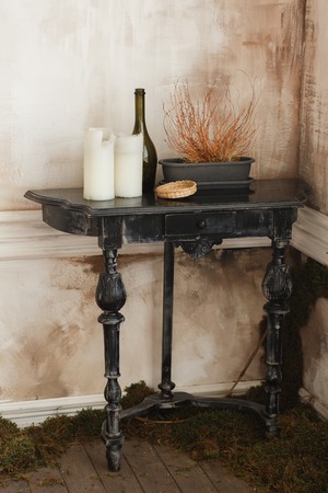 Still-life with an old black wooden table, candles in dirty room cornerの写真素材