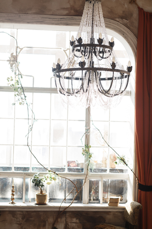 vintage window with bonsai on sill. Big chrystal ceiling light hanging.の写真素材
