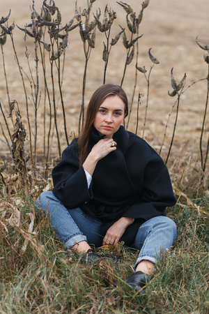 Fashion woman outdoor with unusual grass on background in autumn scenery fieldの写真素材