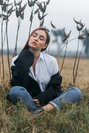 Fashion woman outdoor with unusual grass on background in autumn scenery fieldの写真素材