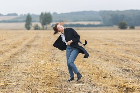 beautiful girl dances outdoors in field at autumn cloudy weatherの写真素材