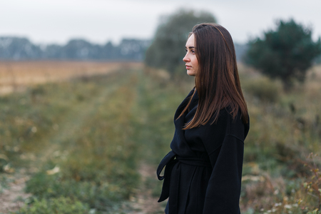 A young woman portrait with village grass road on background. Cloudy autumn weatherの写真素材