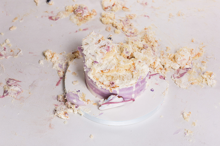 Smashed cake on white table for first birthday. Messy piecesの写真素材
