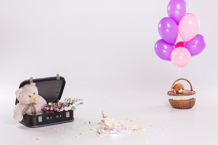 Smashed cake by baby on her first birthday party. Still life with teddy bear in suitcase, ballons. After partyの写真素材