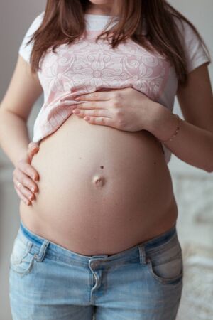 Pregnant woman seven month in jeans. Front view closeupの写真素材
