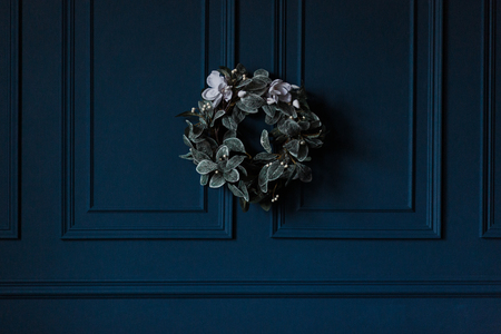 traditional christmas decoration evergreen wreath with white flowers ribbon on dark blue wall backgroundの写真素材