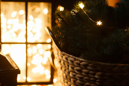 Christmas still life with a wooden basket and golden led garland light on backgroundの写真素材
