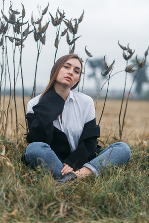Fashion woman outdoor with unusual grass on background in autumn scenery fieldの写真素材