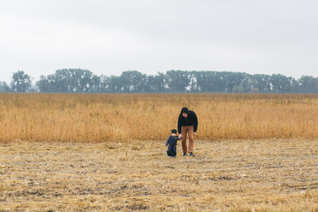 Happy young father and son playing together and having fun in the autumn field. Family, child, fatherhood and nature conceptの写真素材