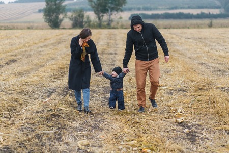 Family walking in autumn field. Falling season. mother, son and fatherの写真素材