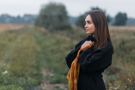 A young woman portrait with village grass road on background. Cloudy autumn weatherの写真素材