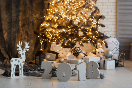 Sign symbol 2018 year under Christmas Tree decorated with golden garland and deer.の写真素材